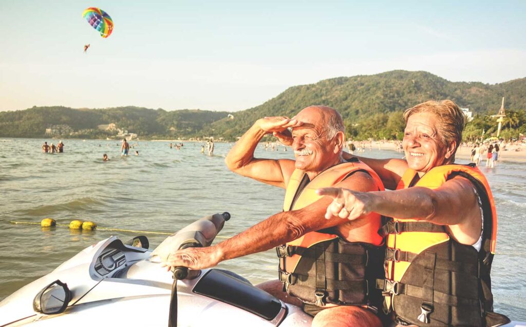 Senior happy couple having fun on jet ski at a beach