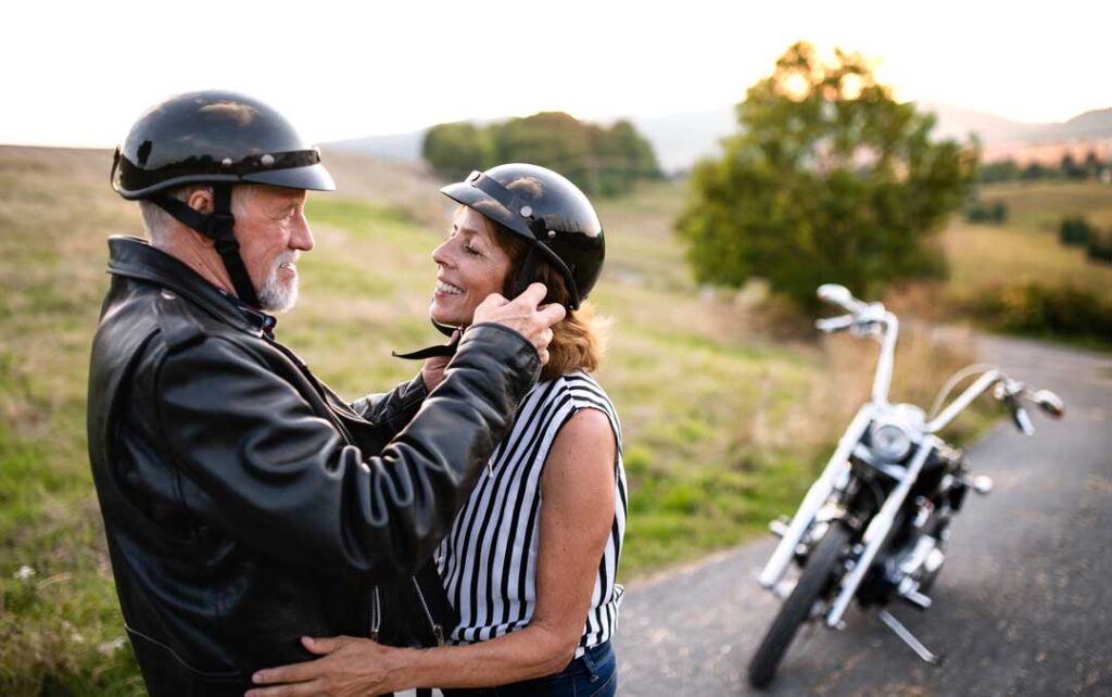  cheerful senior couple travellers in love with motorbike in countryside