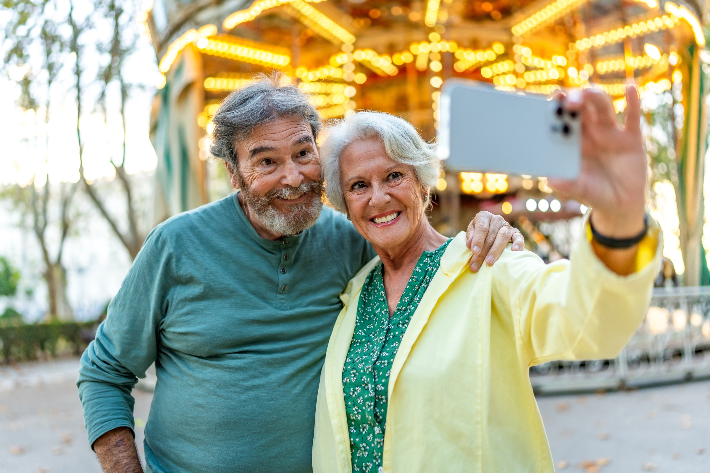 senior couple smiling at camera while talking selfie in a city fair